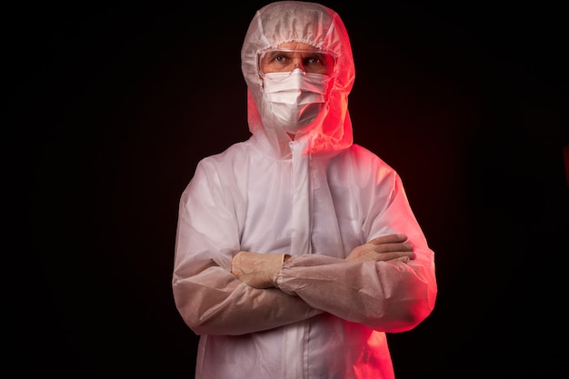 Portrait de médecin homme en costume médical posant isolé sur un espace noir, panneau d'avertissement, avertir les gens contre le virus partout dans le monde, concept covid-19