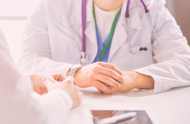 Portrait d'un médecin de sexe masculin avec un ordinateur portable assis au bureau dans un cabinet médical