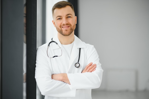 Portrait d'un médecin souriant regardant la caméra avec les bras croisés dans un cabinet médical