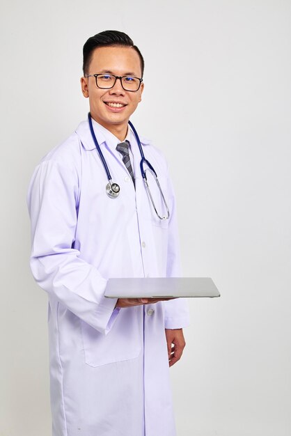 Photo portrait d'un médecin souriant tenant un ordinateur portable sur un fond blanc