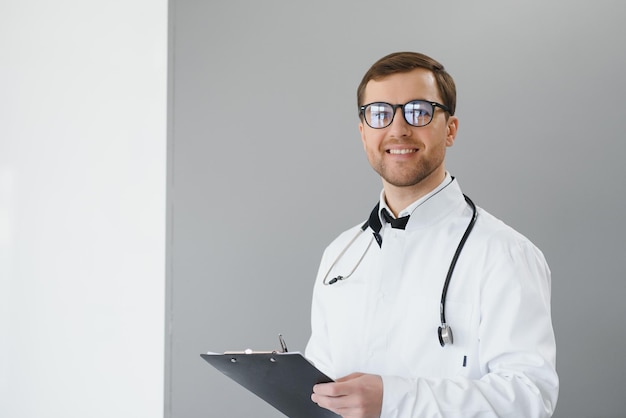 Portrait d'un médecin souriant en uniforme debout dans le hall de la clinique de médecine