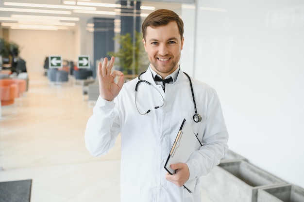 Portrait d'un médecin souriant en uniforme debout dans le hall de la clinique de médecine