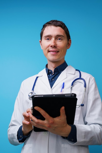 Portrait d'un médecin avec stéthoscope et tablette à la main sur fond bleu