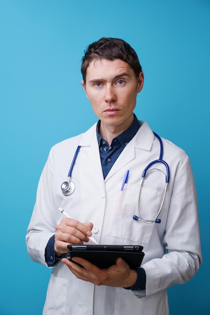 Portrait d'un médecin avec stéthoscope et tablette à la main sur fond bleu