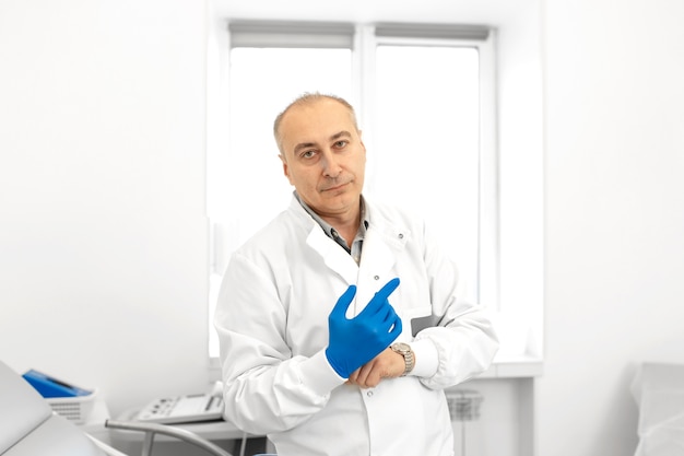 Portrait d'un médecin urologue mettant des gants médicaux avant d'examiner un patient