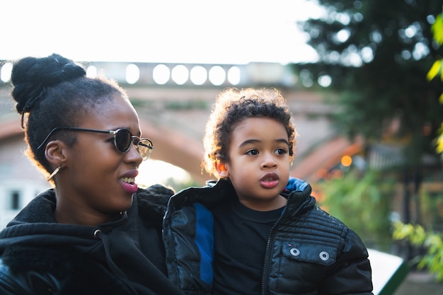 Portrait D'une Mère Afro-américaine Avec Son Fils Debout à L'extérieur Dans Le Parc, S'amusant. Famille Monoparentale.