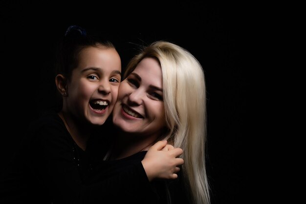 portrait de mère et fille sur fond noir.