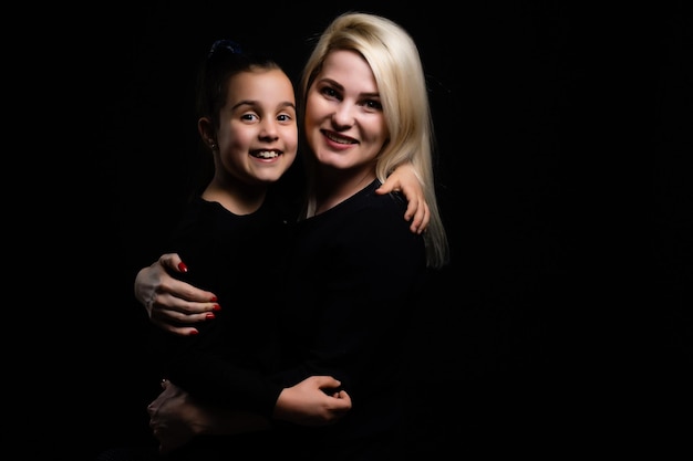 portrait de mère et fille sur fond noir.