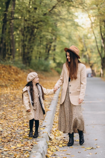 Portrait d'une mère et d'une fille heureuses passant du temps ensemble dans un parc d'automne avec des feuilles jaunes qui tombent