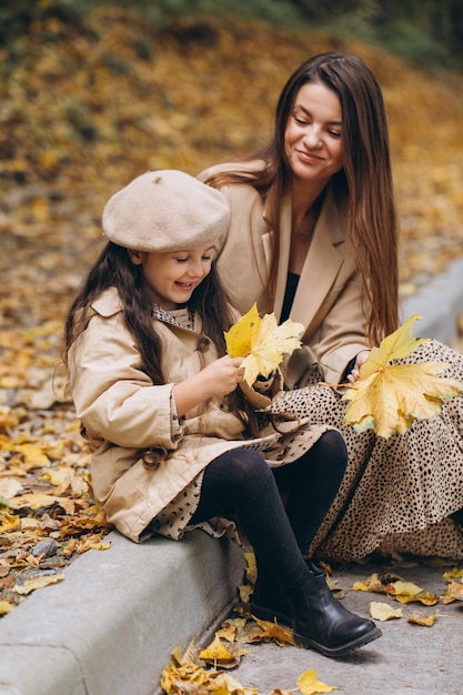 Portrait d'une mère et d'une fille heureuses passant du temps ensemble dans un parc d'automne avec des feuilles jaunes qui tombent