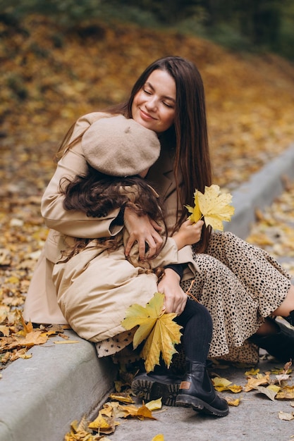 Portrait d'une mère et d'une fille heureuses passant du temps ensemble dans un parc d'automne avec des feuilles jaunes qui tombent