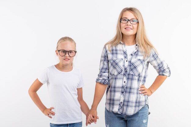 Portrait de mère et fille avec des lunettes sur un mur blanc