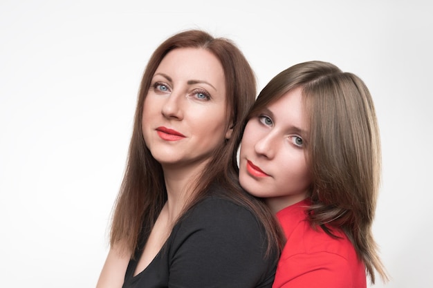 Portrait de mère et fille regardant la caméra Maman en t-shirt noir et adolescente en rouge