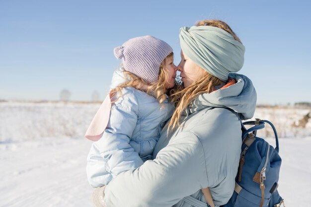 Un portrait d'une mère et d'une fille s'embrassant en hiver dans la nature