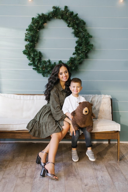 Portrait d'une mère et d'un fils heureux assis sur le canapé du salon décoré pour Noël et le Nouvel An