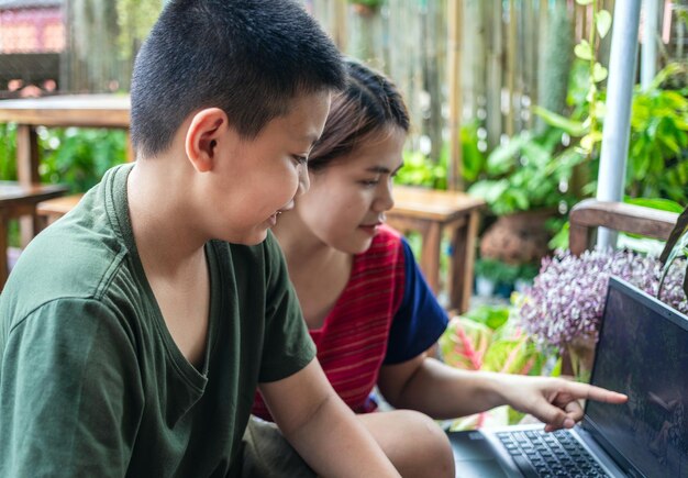 Portrait d'une mère et d'un fils moment spécial La découverte et l'enseignement du jardinage apprennent à faire pousser des fleurs dans des pots grâce au concept d'activité de loisirs d'enseignement en ligne