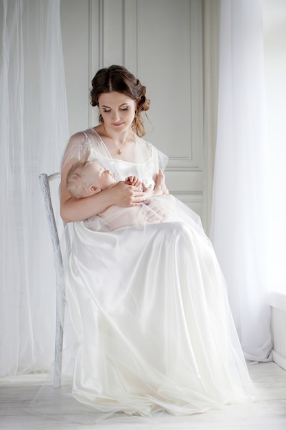 Portrait de mère heureuse et bébé à la maison. Mère tient la petite fille endormie sur les mains