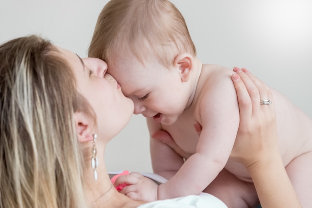 Portrait d'une mère heureuse embrassant un bébé de 9 mois en tête