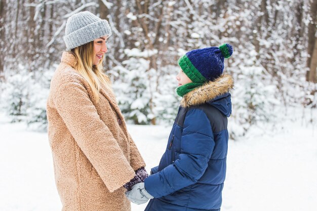 Portrait de mère heureuse avec fils enfant en hiver à l'extérieur. Parc enneigé. Parent célibataire.