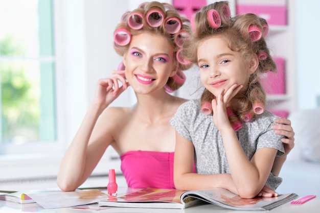 Portrait d'une mère heureuse et d'une petite fille en bigoudis à la maison