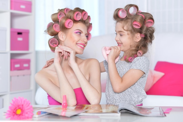 Portrait d'une mère heureuse et d'une petite fille avec des bigoudis