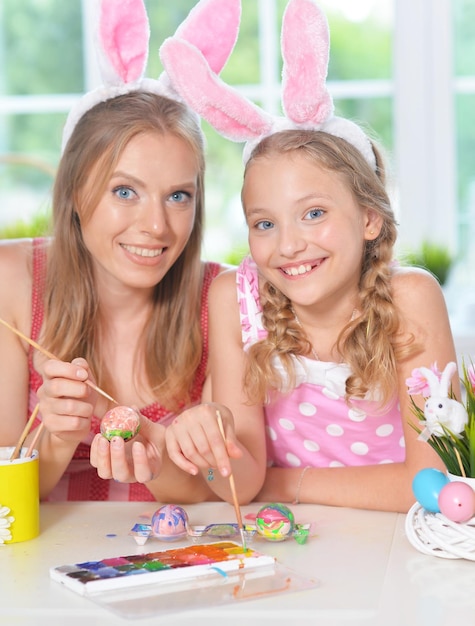 Portrait de mère avec sa fille portant des oreilles de lapin décorant des oeufs de Pâques