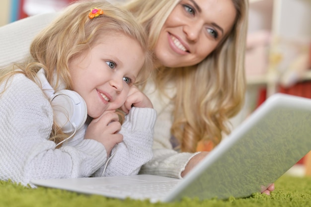 Portrait d'une mère avec sa petite fille à l'aide d'un ordinateur portable