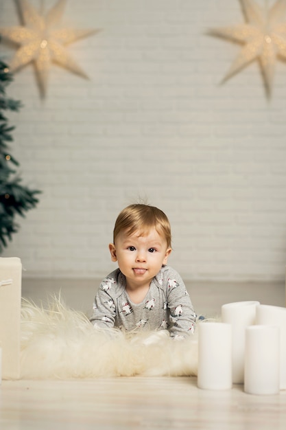 Portrait d'un mignon bambin jouant sur le sol près d'un arbre de Noël. Joyeux Noël et joyeuses fêtes.