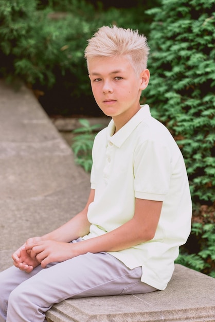 portrait de mignon beau blond onze vieux garçon adolescent assis en plein air dans le parc