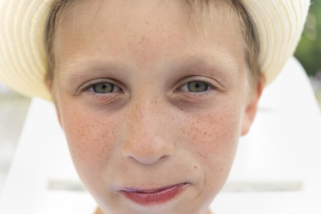 Portrait de mignon beau garçon au chapeau avec des taches de rousseur en gros plan un garçon avec un regard sérieux et triste et