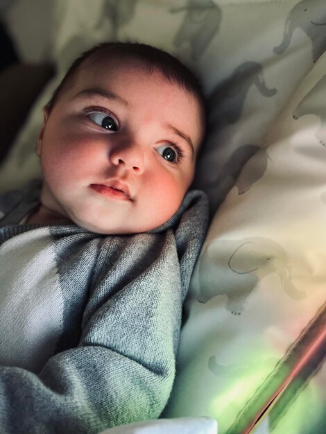 Photo portrait d'un mignon bébé qui dort sur le lit en regardant la télévision