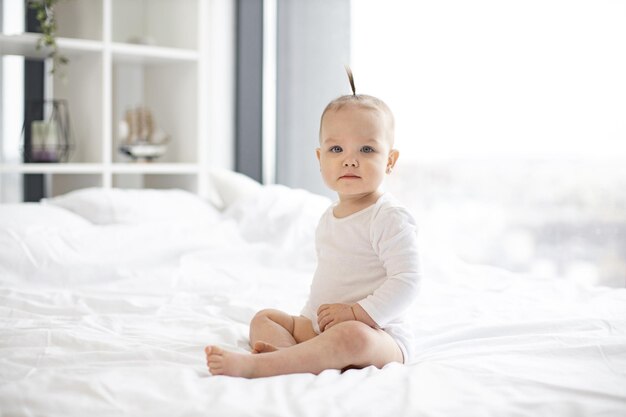 Photo portrait de mignon petit bébé assis sur une couverture blanche