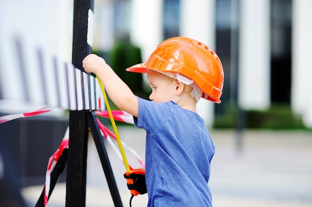 Portrait de mignon petit constructeur de casques avec règle travaillant à l&#39;extérieur