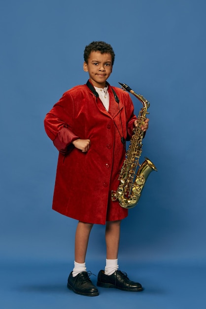 Portrait d'un mignon petit garçon africain portant une énorme veste d'homme et des chaussures comme un homme de jazz jouant sur