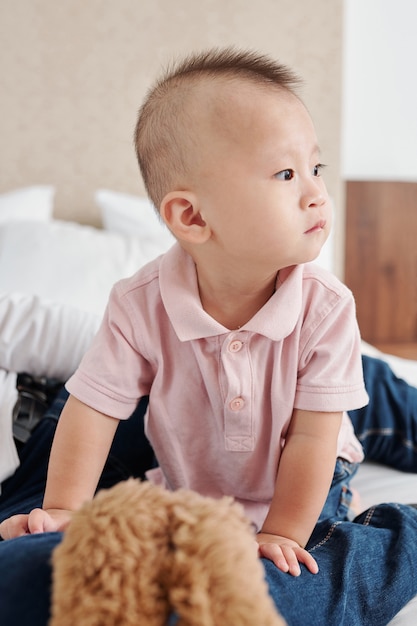 Portrait de mignon petit garçon asiatique curieux rampant sur le lit et regardant autour de