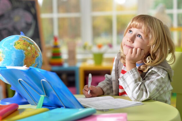 Portrait de mignon petit garçon aux longs cheveux blonds fait ses devoirs