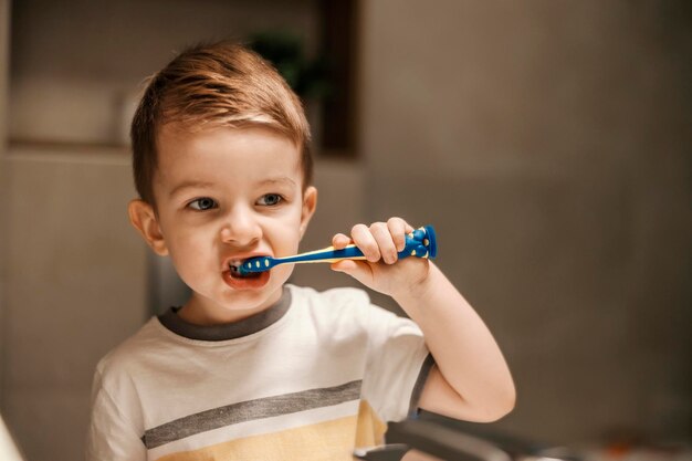 Portrait d'un mignon petit garçon debout devant le miroir et se brosser les dents