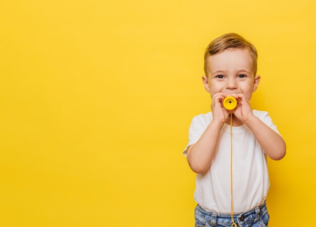 Portrait d'un mignon petit garçon riant sur fond jaune