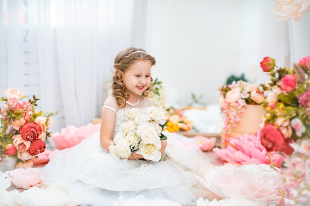 Portrait mignonne petite fille en belle robe ondulée, avec bouquet de roses.