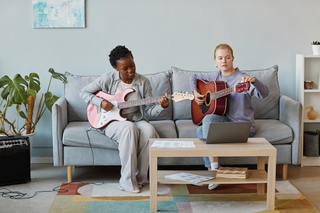 Portrait minimal de deux jeunes femmes jouant de la guitare ensemble en studio et composant de la musique