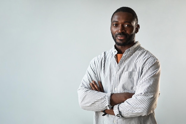 Portrait minimal à la taille d'un homme d'affaires afro-américain prospère debout avec les bras croisés agai