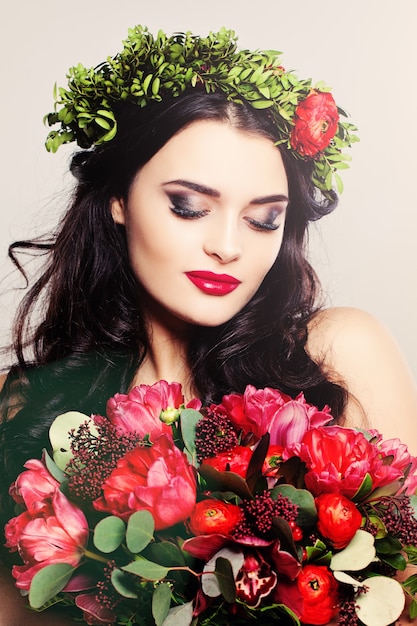 Portrait de mode de beauté. Belle femme aux cheveux bouclés, maquillage et fleurs