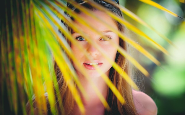 Portrait de mode d'une belle jeune fille blonde debout dans les paumes et regardant avec ses yeux parfaits sur Bali