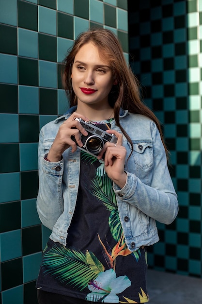 Portrait de mode ensoleillé de style de vie de jeune femme élégante marchant dans la rue, avec appareil photo, souriant profiter des week-ends, faire une photo de son voyage, ancien appareil photo rétro, vintage