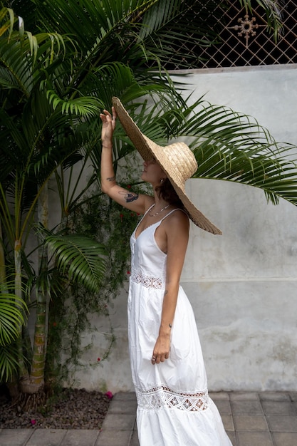 Portrait de mode d'une femme élégante vêtue d'une robe blanche et d'une grande paille géante