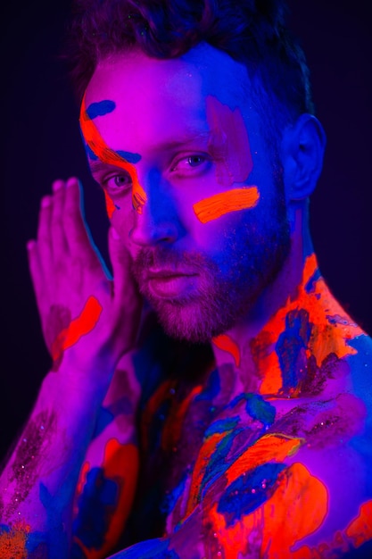 Portrait de mode d'un homme avec de la peinture ultraviolette sur son corps et de la lumière au néon dans un style cyberpunk