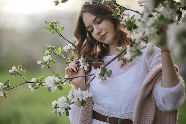 portrait de mode printanier d'une jeune fille dans un jardin de cerisiers en fleurs, tendresse du matin