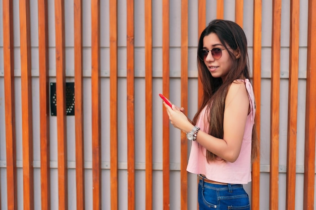 Portrait de mode d'une très jeune femme avec des lunettes de soleil et un téléphone portable.