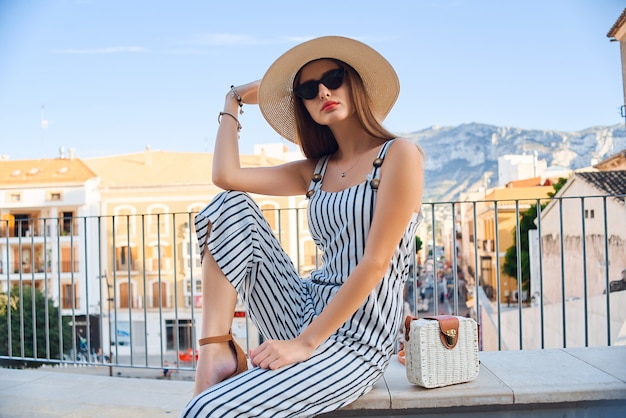 Portrait de mode de vie ensoleillé de jeune femme élégante, marchant dans la rue.