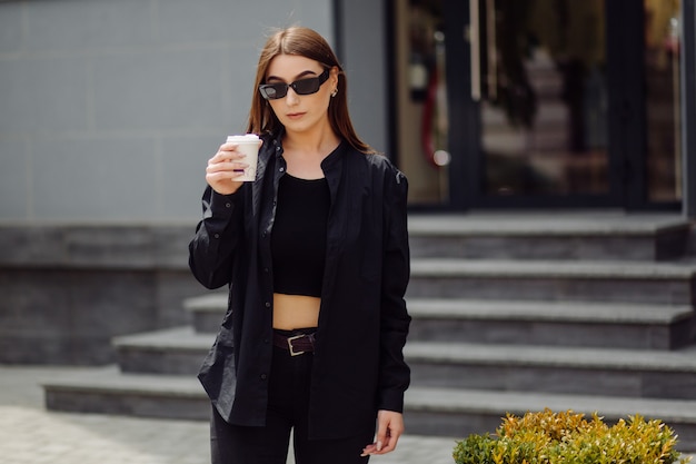 Portrait De Mode De Vie En Plein Air D'une Superbe Fille Brune. Boire Du Café Et Marcher Dans La Rue De La Ville.